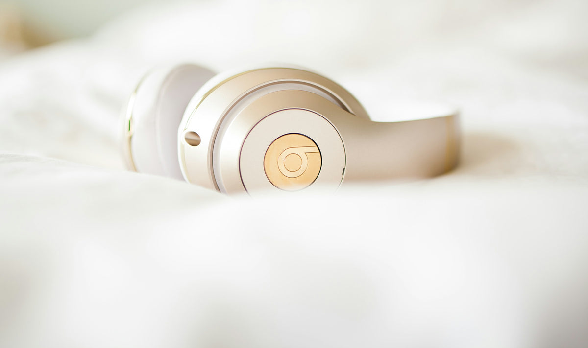 Casque audio crème posé sur des draps blancs