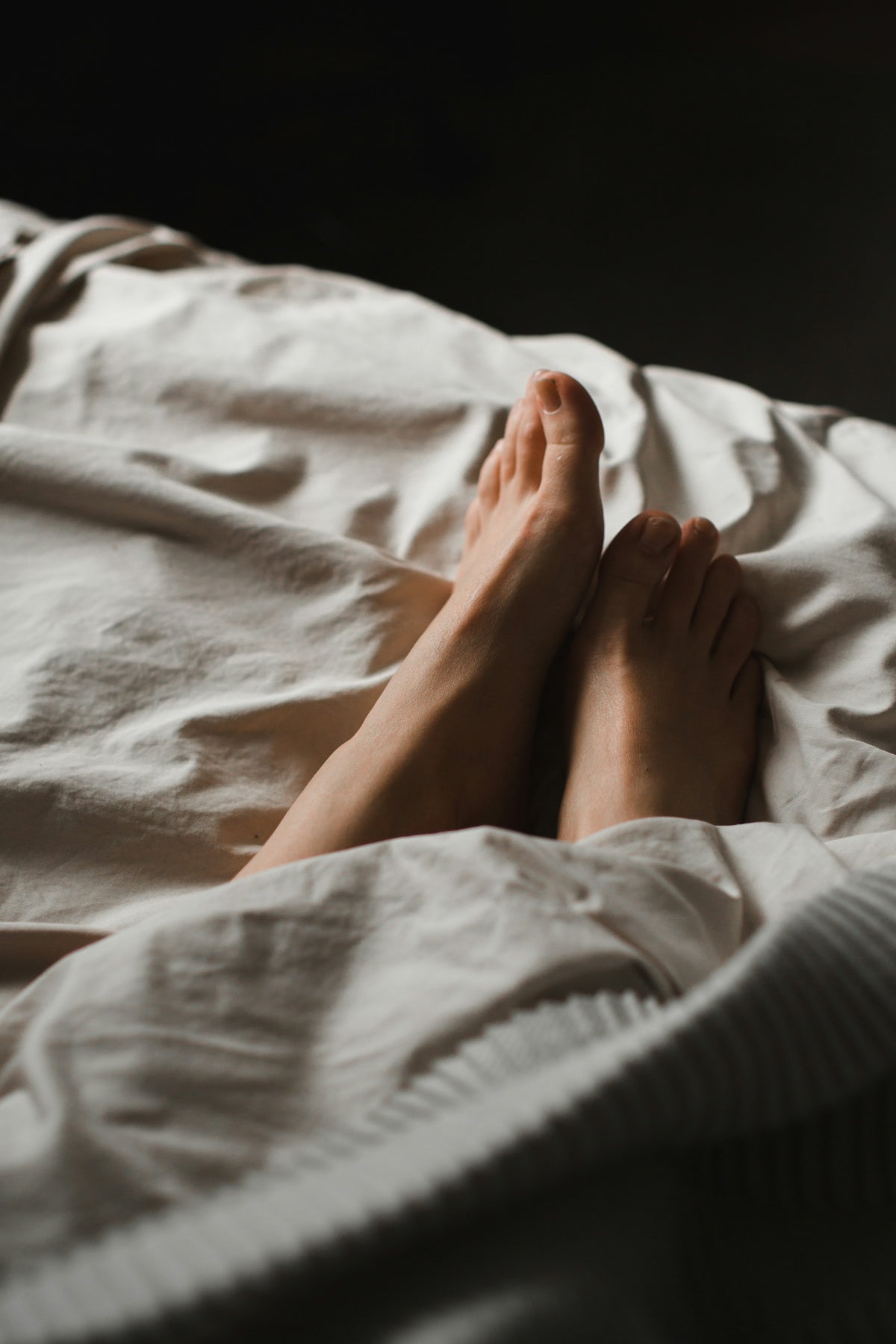 Pieds nus détendus sur des draps en lin beige