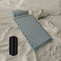 Tapis d’acupression gris et son coussin posés sur un lit
